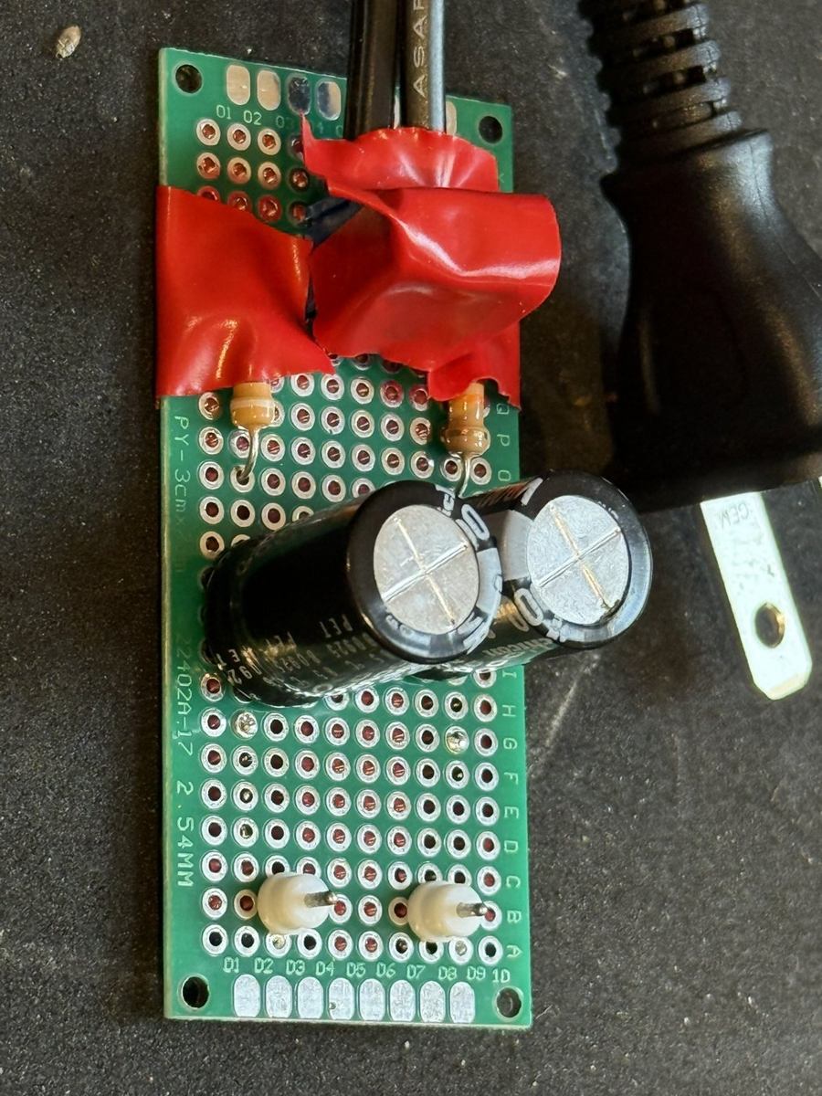 The AC-mains DC-offset measurement filter: a hand-built green perfboard with large capacitors, mains-rated wiring, and red insulating covering.