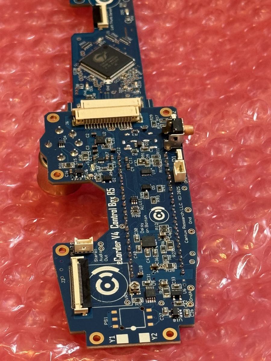 eCorder V4 control board revision 5: a blue instrument-shaped printed circuit board with a touch controller, fine-pitch connectors, and power management circuitry, resting on pink anti-static bubble wrap.