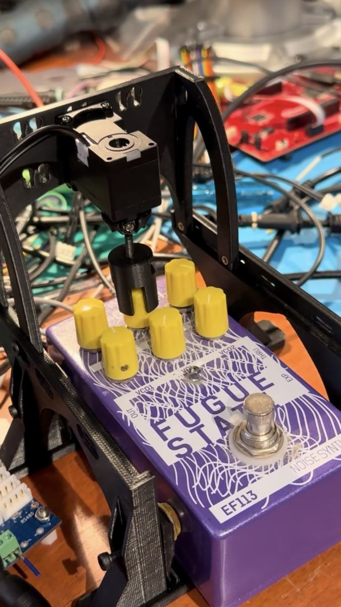 The knob turner: a 3D-printed frame holding a smart servo above a purple guitar effects pedal, driving one of its yellow knobs through a compliant coupling.